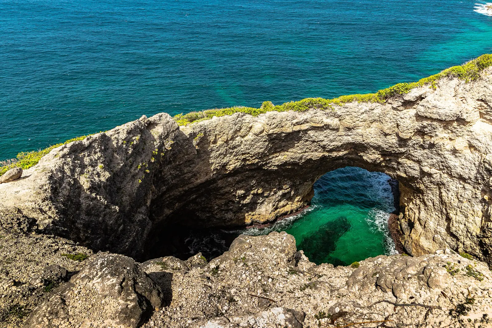 L'arche de la Gueule Grand Gouffre vue depuis le bord du gouffre, avec l'eau turquoise au fond et l'océan au-delà